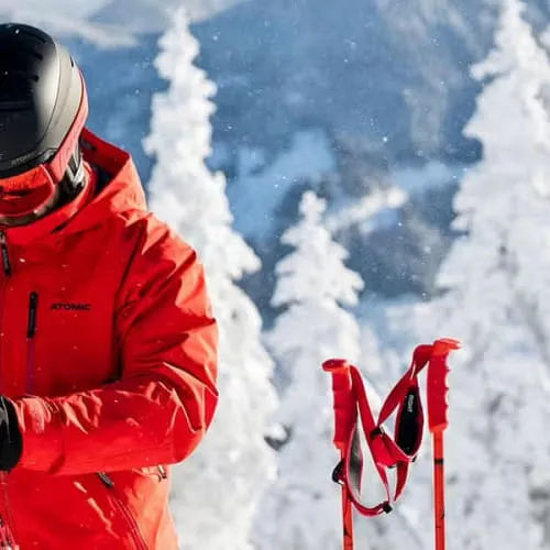 Skileraar in rode jas tegen sneeuwbergen