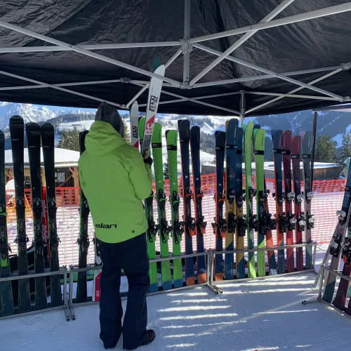 Skikeuze onder een tent met veel ski's.